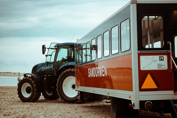 Der Traktorbus wird Sandwurm genannt und ist ein Anhänger mit Sitzbänken der von einem Traktor gezogen wird.